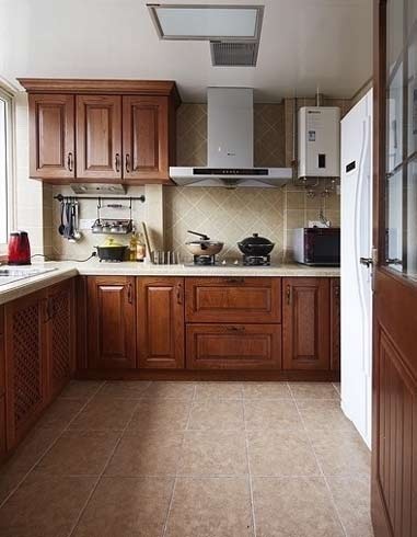 L型的厨房布置也是比较常见的，这里的橱柜仍然选用实木的材质，利用转角的设计很好的节约了空间，又能形成烹饪区和洗涤区的完美工作空间，下面的地柜和上面的吊柜可以很好的进行储物。