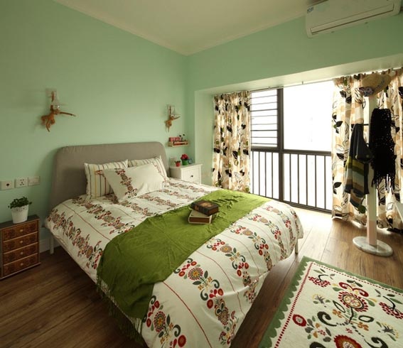 果绿色的卧室背景墙是偏冷色调的，一般很少有很用，但是这个颜色的选择也是要根据个人喜好的，浅浅的绿色调，渲染出卧室清新自然的氛围，卧室的地毯很漂亮和被褥采用同一花纹，增添房间的和谐感。