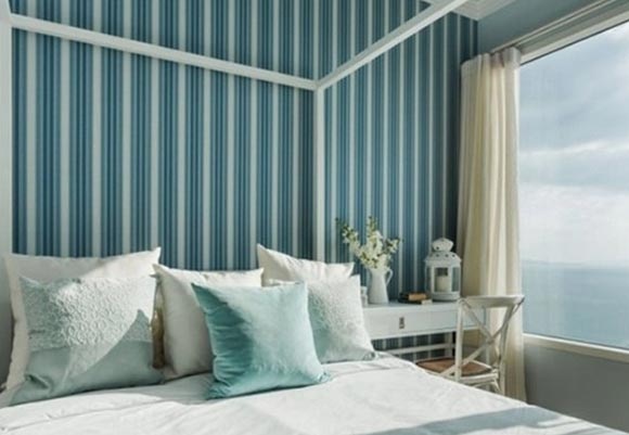 蓝白相间的条纹墙壁，简单的床上搭配给人一种清新爽朗的愉悦感。