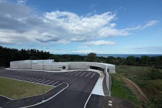 日本 atelier BNK 公司在日本北海道函馆设计了绳纹文化交流中心。建筑作为博物馆使用的同时，也是一个路边服务站，并将纪念品商店、停车场、洗手间和信息设施精心整合融入建筑。然而，建筑最主要的吸引力来自于博物馆本身，这里有一个永久性的展厅，展示了绳纹时代的陶器和金属物件，其中空心粘土人像“chuku土偶”哪怕是对整个北海道来说也是独一无二的。建筑独具匠心的弧形结构坐落于主要道路与kakinoshima遗迹之间，作为新与旧之间的屏障。曲线形状和建筑材料的使用受到绳纹时代的影响，舒缓的墙面由雪松板纹理和不同厚度的裸露混凝土组成。