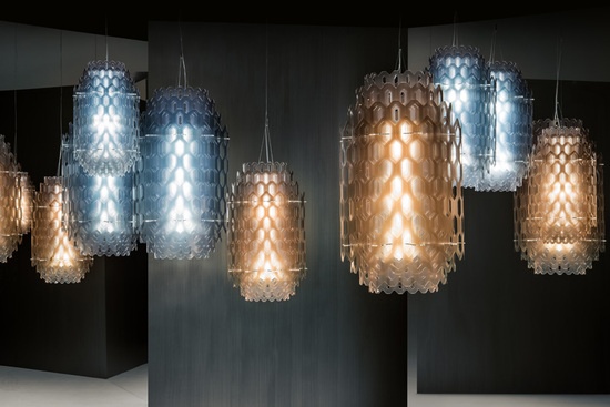 doriana and massimiliano fuksas 为slamp 品牌打造了‘chantal’系列灯具，创造了一个幻影世界。这一系列橙色、蓝色和白色的吊灯是基于设计师对二维元素转化为一系列无穷无尽的多层叠加体量的想法而产生。‘chantal’系列灯具由多层cristalflex和lentiflex材料构成，材料上挖了多个六边形的孔洞，多个孔洞共同构成了一种让人联想起波浪的效果，以及多层等比缩小的材料的透明感逐渐变淡直至消失的效果。‘chantal’系列灯具于2015米兰设计周期间在euroluce展区展出。